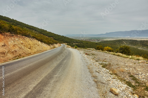 The road leading into the distance  the mountains on the horizon and the cloudy sky