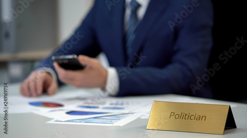 Successful politician studying opinion polls before elections, using smartphone