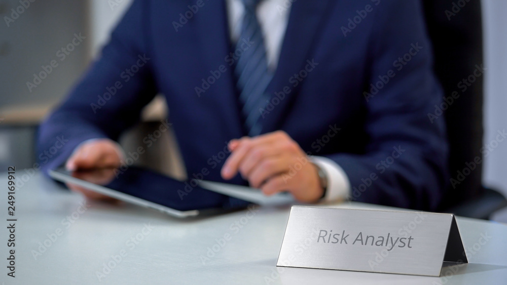 Risk analyst reading market report on tablet pc, checking new project chances Risk analyst reading market report on tablet pc, checking new project chances