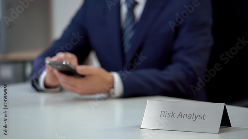 Busy male risk analyst viewing files on smartphone, resolving business problem