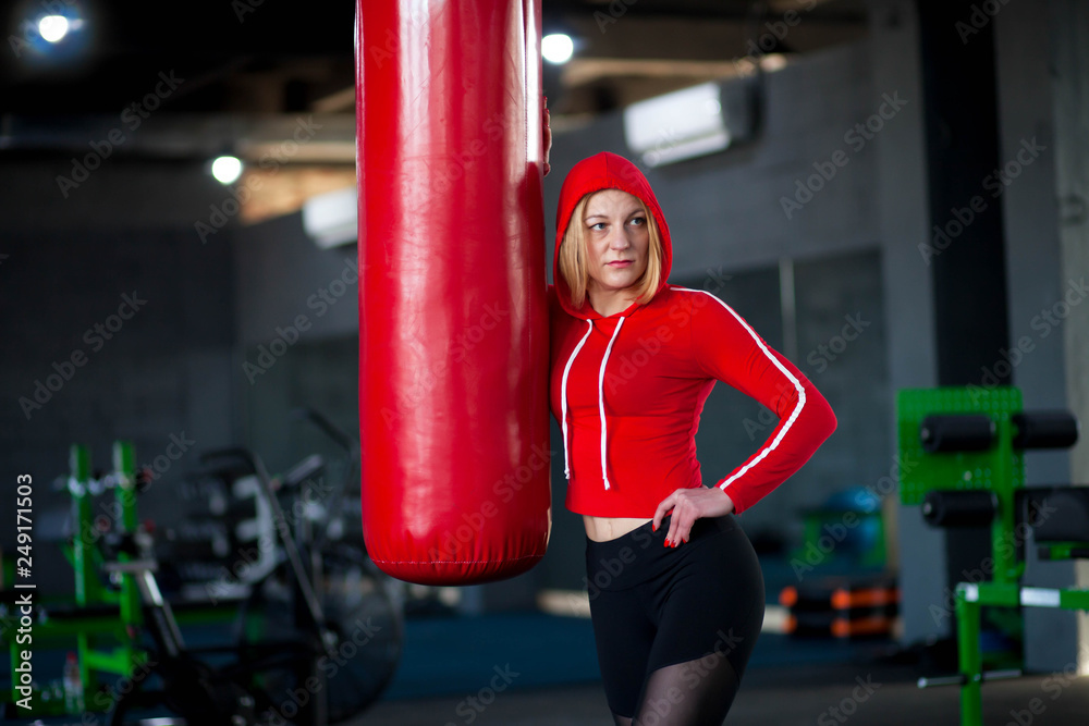 Girl standing near the punch bag. Kickboxer after workout with punching bag. Girl boxer