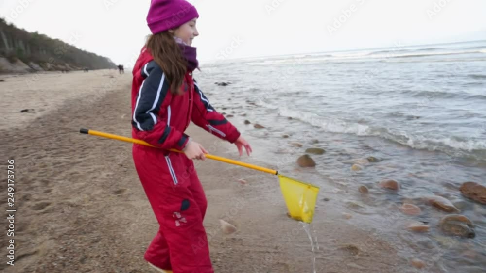 Young girl playing in the water in sea with fishing net.