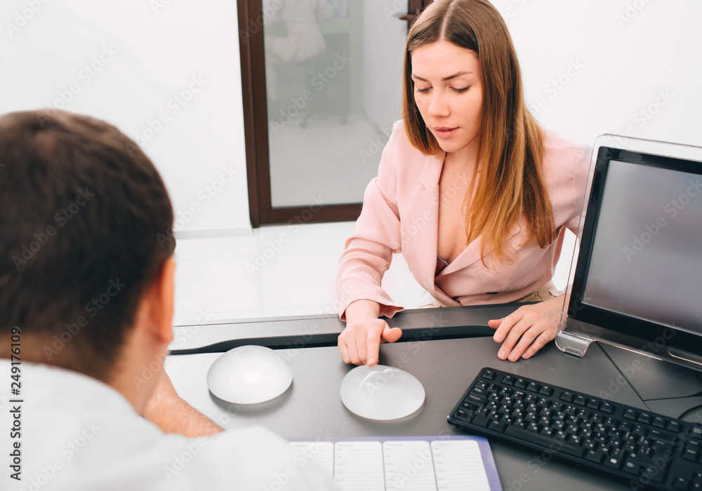Young woman during the consultation and selection of breast silicone implants. breast augmentation Young woman during the consultation and selection of breast silicone implants. breast augmentation