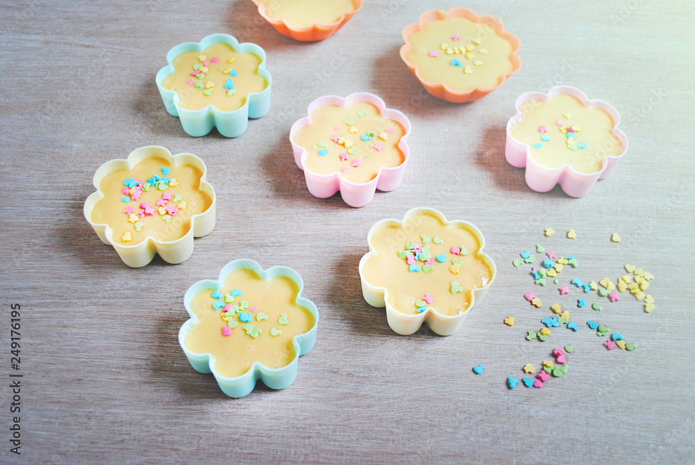 Dough is poured into baking tin. Rows of colorful cups. Muffins preparation at home. Dough is poured into baking tin. Rows of colorful cups. Muffins preparation at home.