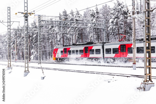 Red electric train moves through winter forest photo