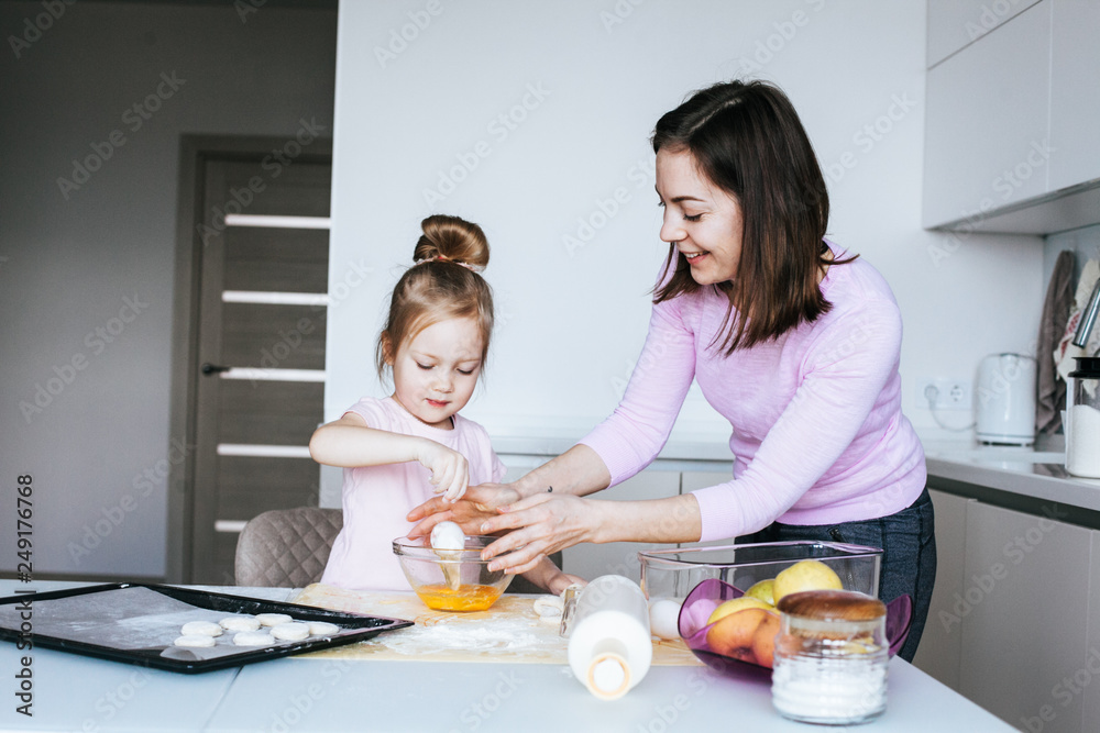 A mother and her daughter busy baking at home in the kitchen and having fun A mother and her daughter busy baking at home in the kitchen and having fun