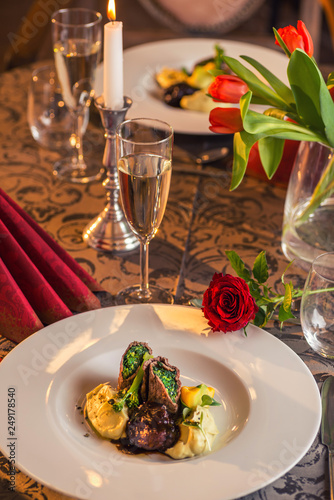 baked beef with baby patizone, sauce and spinach served on white plate with flowers and champagne, romantic time on valentines day