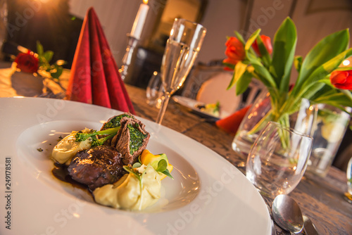 baked beef with baby patizone, sauce and spinach served on white plate with flowers and champagne, romantic time on valentines day