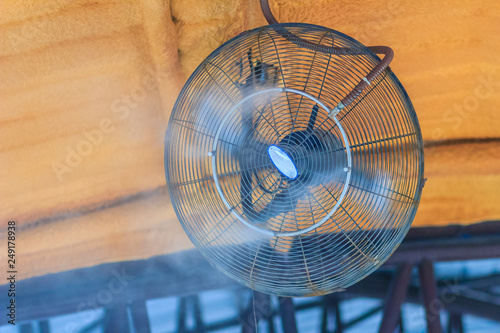 Electric vapor cooling fan on the ceiling, water mister fan blows cool water into the air to cool down the area outside on a hot summer day.