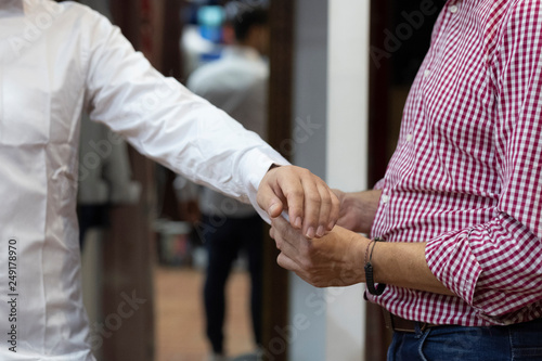 tailor adjusting white shirt with cufflinks to a customer