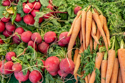 A display of carrots and radishes for sale on a market stall