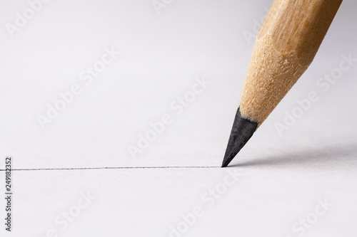 Close up of pencil with drawing line on textured white paper photo