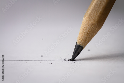 Close up of broken pencil with drawing line on textured white paper