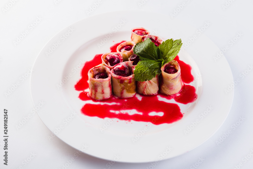 rolled pancakes stuffed with berries called white plate on a light background (close) rolled pancakes stuffed with berries called white plate on a light background (close)