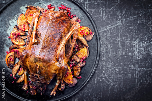 Traditional roasted stuffed Christmas duck with orange and pomegranate as top view on a board