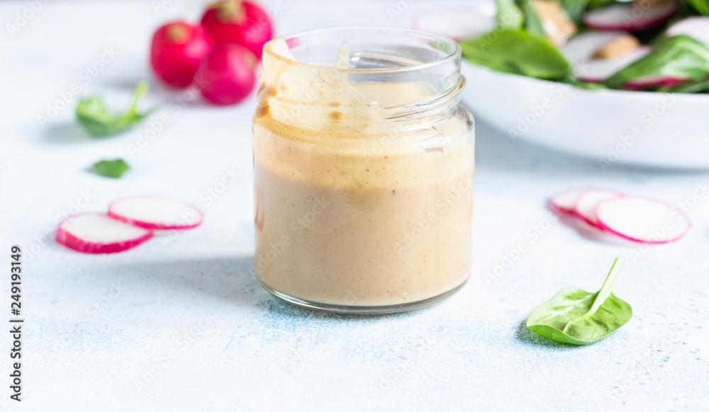 Spinach and radish salad with peanut butter dressing. Light grey concrete background. Copy space. Healthy vegetarian food. Spinach and radish salad with peanut butter dressing. Light grey concrete background. Copy space. Healthy vegetarian food.