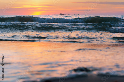 Sunset over the sea. Reflection of sunlight in the sea waves. Red and yellow sky in the rays of the sunset.