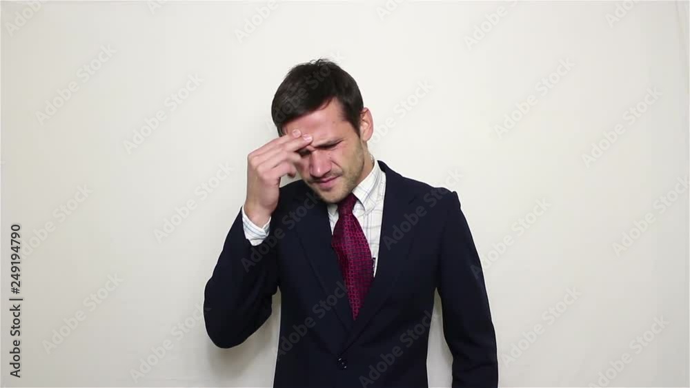 Young handsome businessman in blue suit suffers from headache..Portrait on a white background. Young handsome businessman in blue suit suffers from headache..Portrait on a white background.