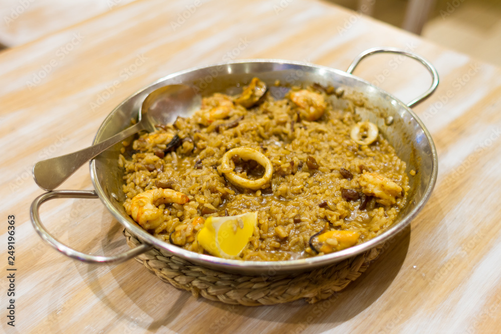 Traditional seafood paella in the pan on a wooden table Traditional seafood paella in the pan on a wooden table