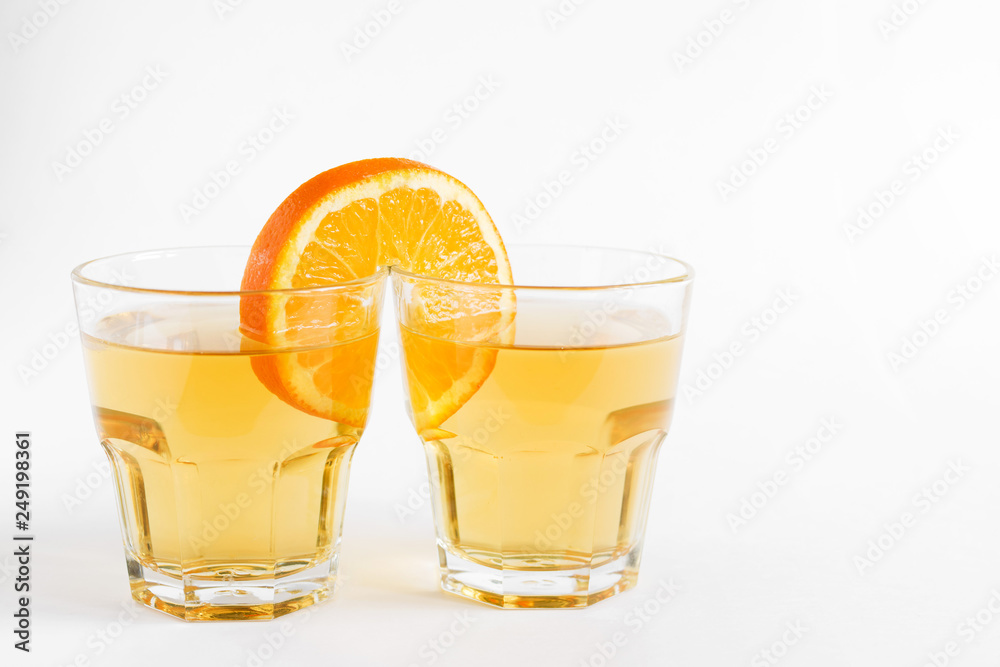 One orange slice combines two glasses with juice on a light surface. Conceptual image of a couple, love, family