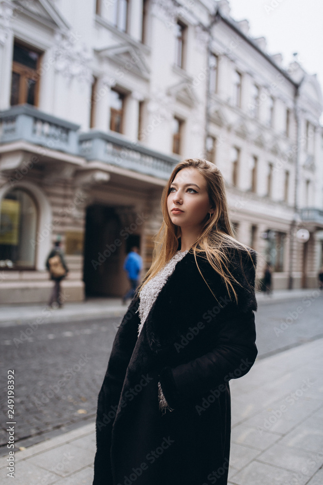 Fototapeta premium Young blondie business woman rushing to a business meeting. Walking along old historic european town 