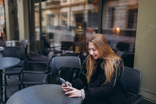 Blondie young girl in street outdoor cafe with smartphone chating and communicate