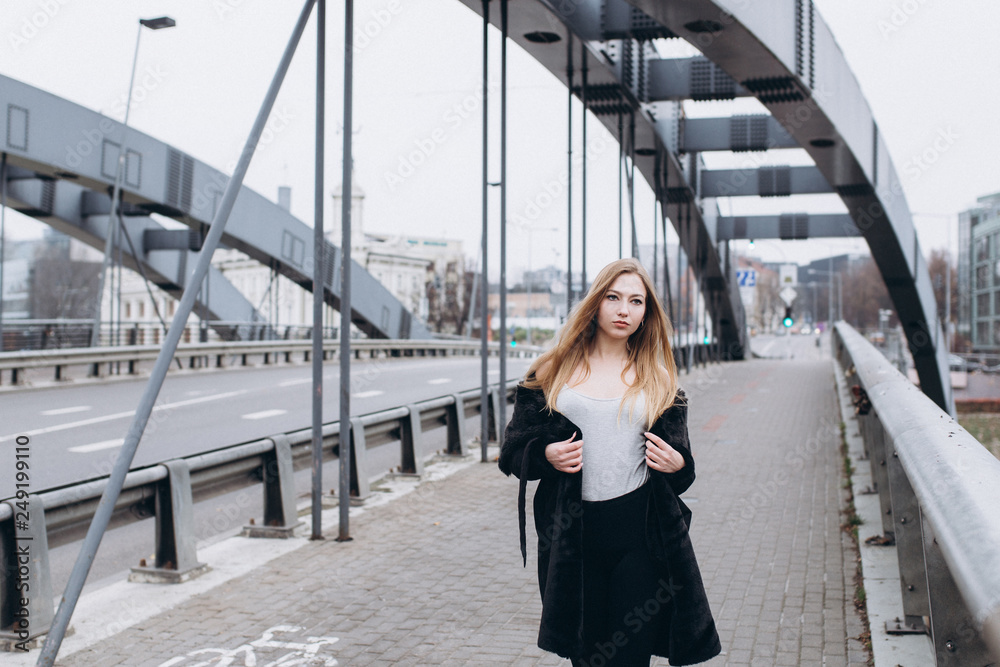 Young blondie sexy sensual girl go across the bridge in black coat. Outdoor  portrait. Casual, lifestyle concept Stock Photo | Adobe Stock