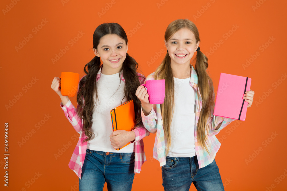 Friends spend leisure reading books. Having break relax. Drinking tea while reading book. Sisters relaxing with drink. Reading pleasant activity. Girls kids with books and tea mugs orange background Friends spend leisure reading books. Having break relax. Drinking tea while reading book. Sisters relaxing with drink. Reading pleasant activity. Girls kids with books and tea mugs orange background