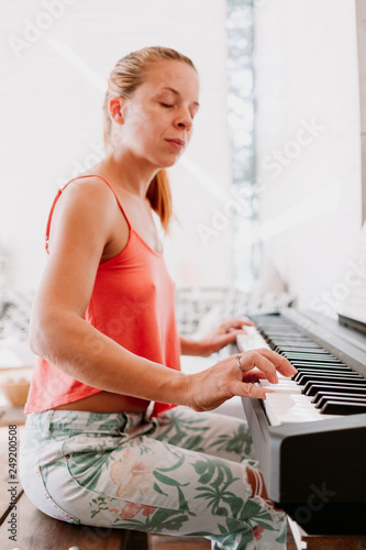 Young woman enjoying playing electric piano at home