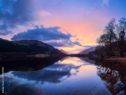 Szkocki piękny kolorowy zachód słońca z Loch Voil, górami i lasem w Loch Lomond & The Trossachs National Park