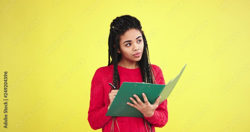 Beautiful young woman office worker in the studio with a yellow background wall writing something on the office map she have a serious mood in front of the camera Beautiful young woman office worker in the studio with a yellow background wall writing something on the office map she have a serious mood in front of the camera