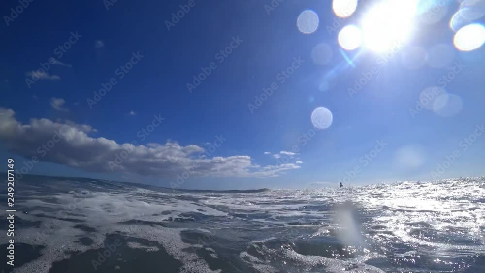 Camera is being hit by a wave in the Atlantic ocean on a sunny day, underwater shot with bubbles 