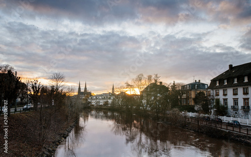 Strasbourg sunset with cloudy and sunny sky with Reformed Church Saint Paul and Ill river, cars parked and houses © ifeelstock