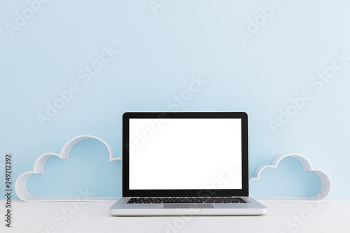 Computer mock up near blue wall with clouds. Creative workspace.