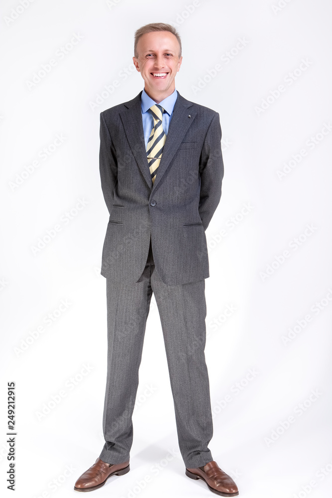 Smiling Happy Caucasian Businessman Posing Against White with hands Folded Behind. Smiling Happy Caucasian Businessman Posing Against White with hands Folded Behind.