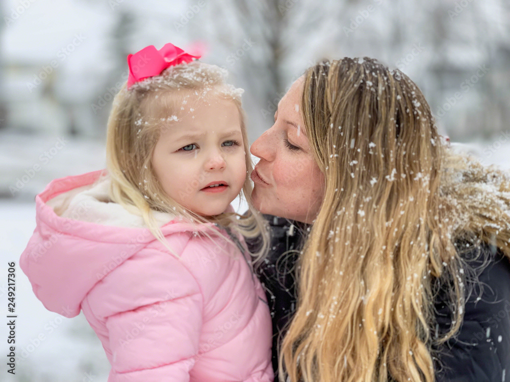 Obraz premium Young mother holding little girl in the snow
