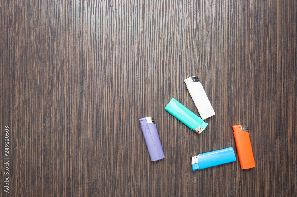 Naklejka premium Multicolored lighters on a dark wooden table