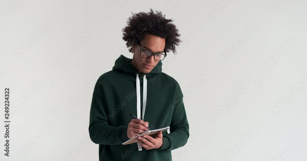 African american man planning and writing shopping list in notepad