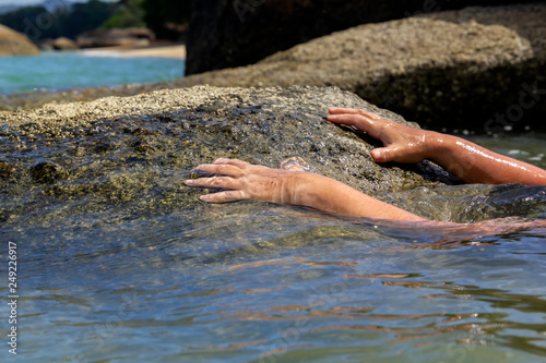 woman s hand out of the water trying to grab the coastal stone and escape from the sea. Close-up. Copy space
