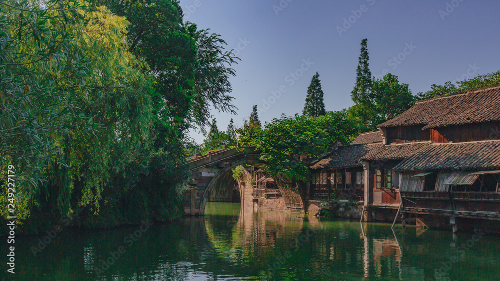 Traditional Chinese houses and bridge by water under blue sky, in the old town of Wuzhen, China Traditional Chinese houses and bridge by water under blue sky, in the old town of Wuzhen, China