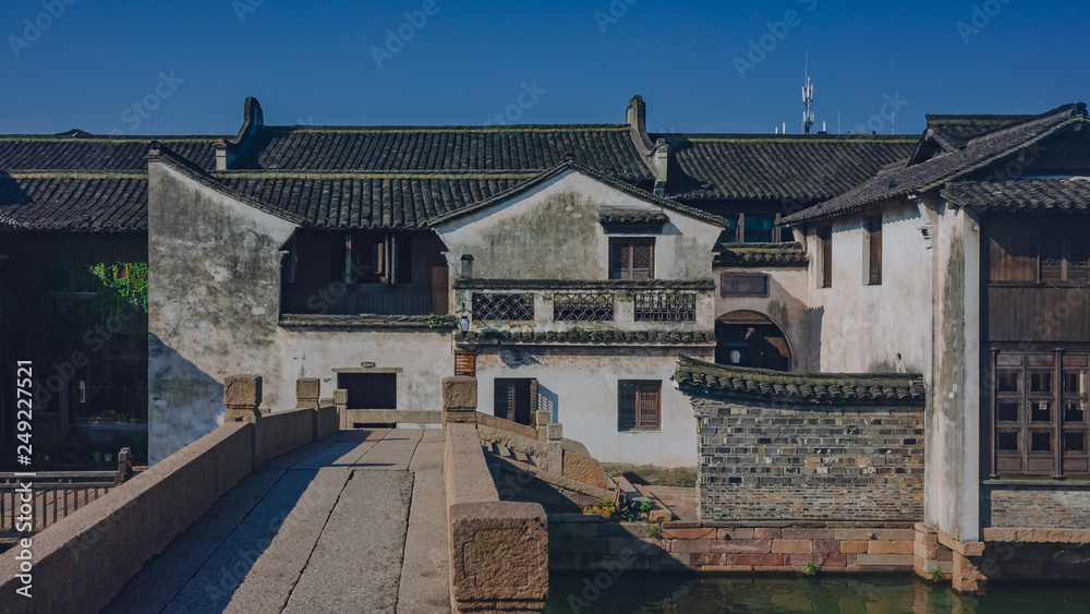 Fototapeta premium Traditional Chinese houses and bridge by water under blue sky, in the old town of Wuzhen, China
