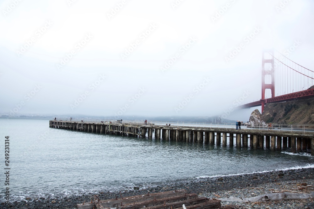 Obraz premium Golden gate bridge on foggy day with pier below in the foreground 