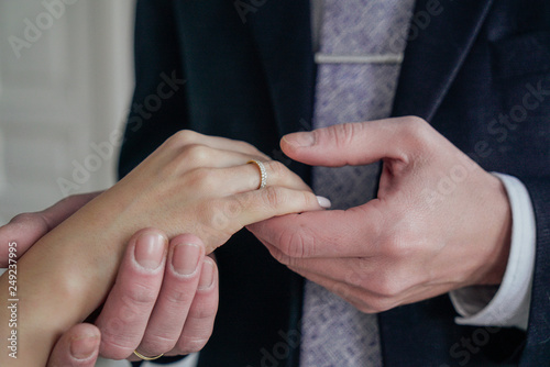Man holding woman's hand with engagement ring, wedding day