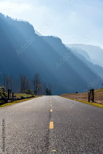 Road rests on a mountain ridge lit by oblique rays of the sun in Colombia River Gorge photo