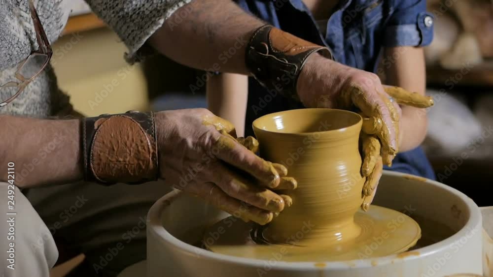 Man's hands working with clay on pottery wheel