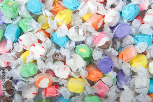 Background of salt water taffy in various flavors and colors wrapped in white transparent paper. Salt water taffy is sold widely on the boardwalks in the U.S. and Canada. photo