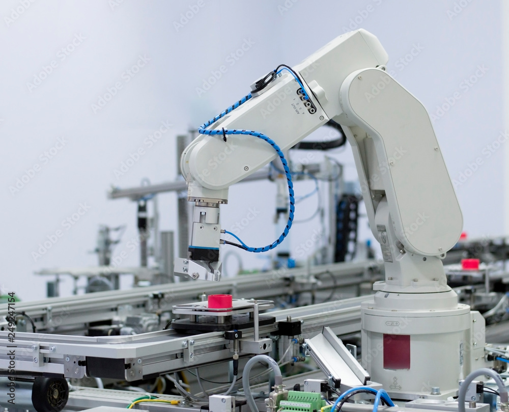 Focus on robot arm's gripper. Industry 4.0 concept; artificial intelligence in smart factory. Robot picks up the product from automated car on the manufacturing line. Selective focus.