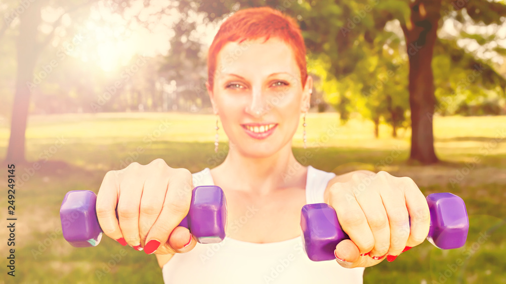 Happy young woman exercising with dumbbells in park Happy young woman exercising with dumbbells in park