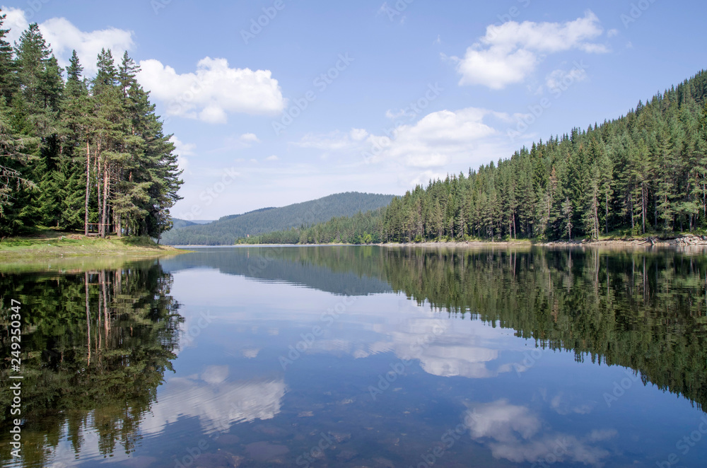 Lake Shiroka Polyana in the Rhodopes  with reflections of pines and clouds, Bulgaria