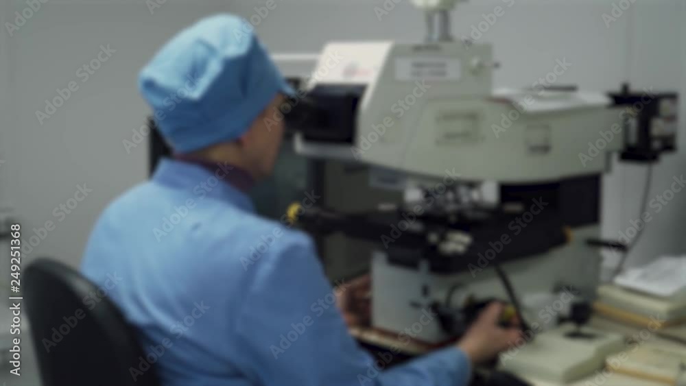 Blurred view, scientists staff work in laboratory, looking through a microscope, quality control and work on special equipment. Blurred view, scientists staff work in laboratory, looking through a microscope, quality control and work on special equipment.